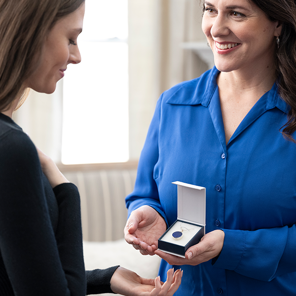 Woman showing another woman a remembrance pendant
